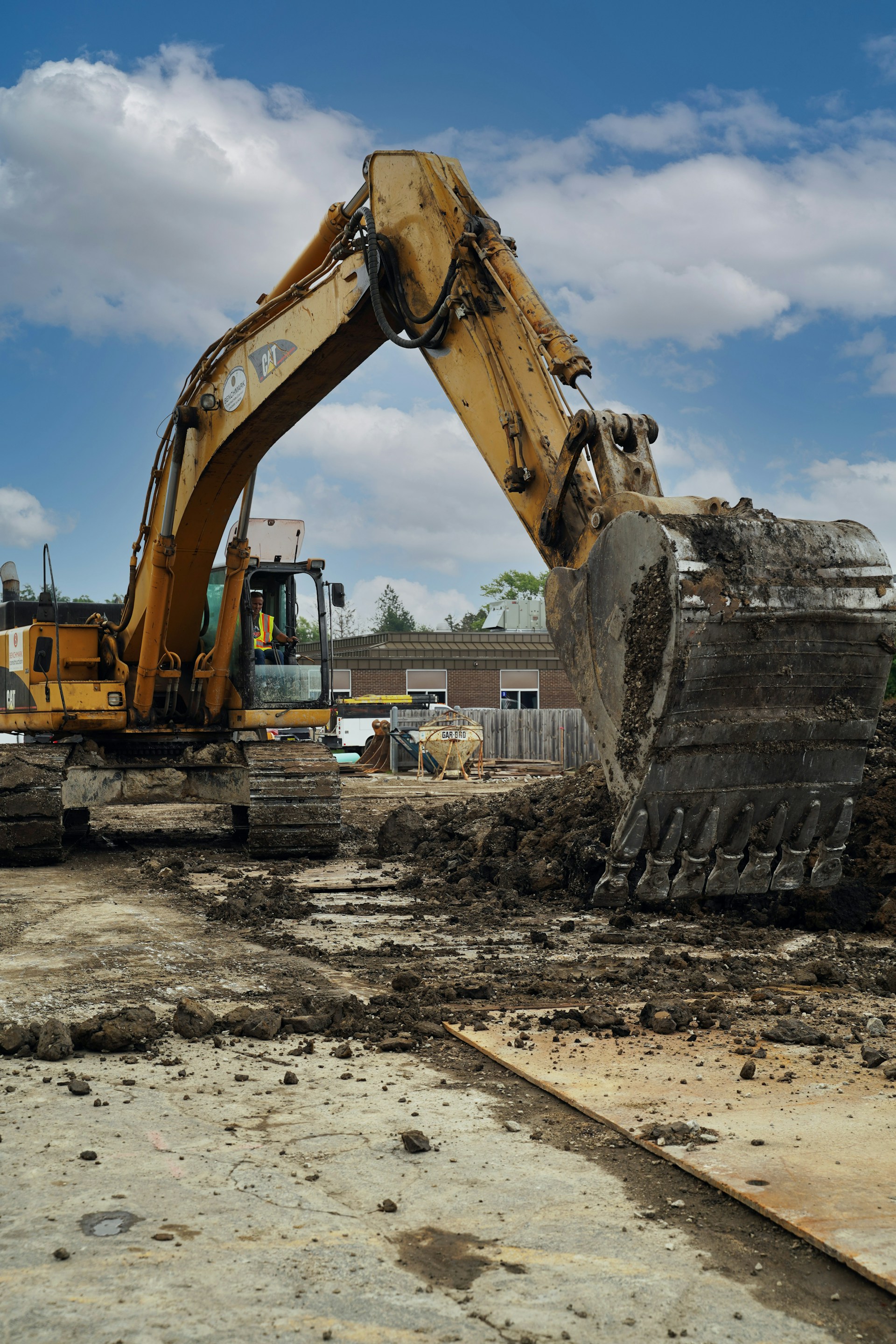 A yellow excavator is seen working diligently on a construction project, moving materials at a building location.