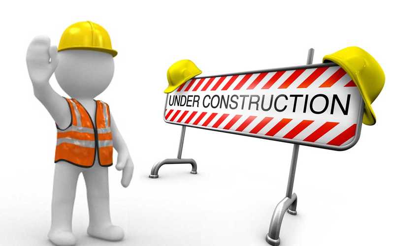 Man standing next to an 'under construction' sign