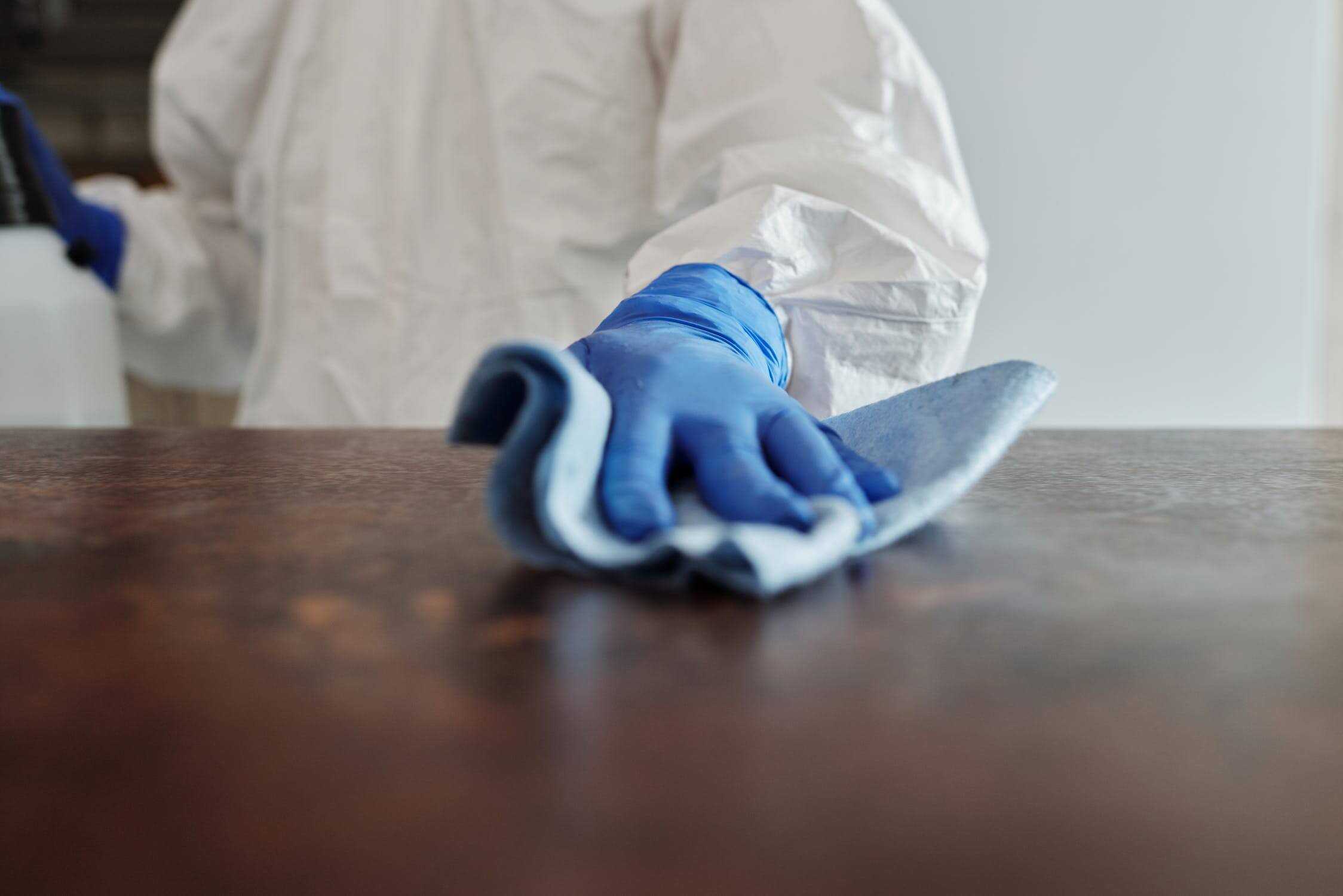 Close-up of a person's hand in a hazmat suit while they're cleaning