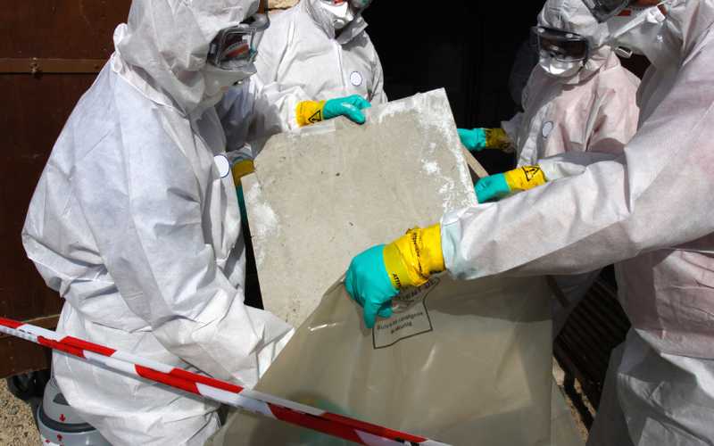 Three people handling asbestos material