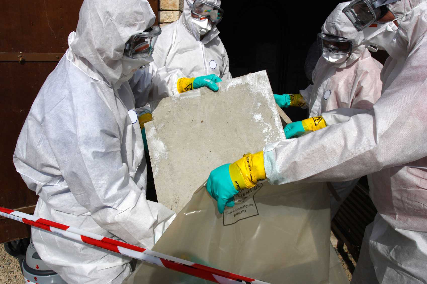 Three people handling asbestos material